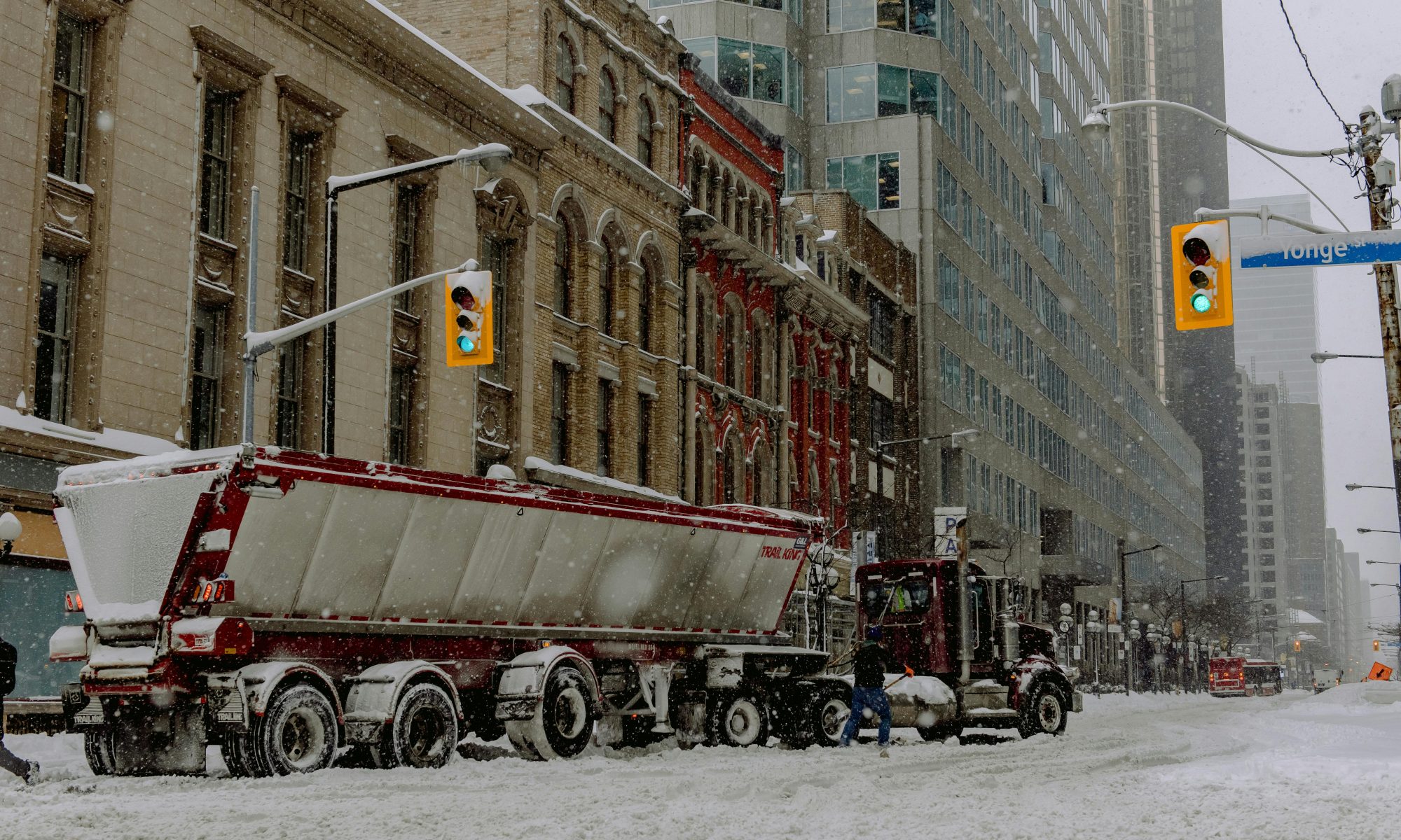 Semi-trailer and truck within the city while snowing - photo by Harrison Haines