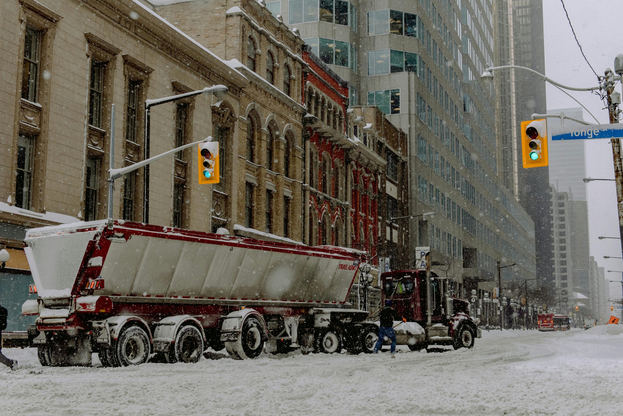 Semi-trailer and truck within the city while snowing - photo by Harrison Haines